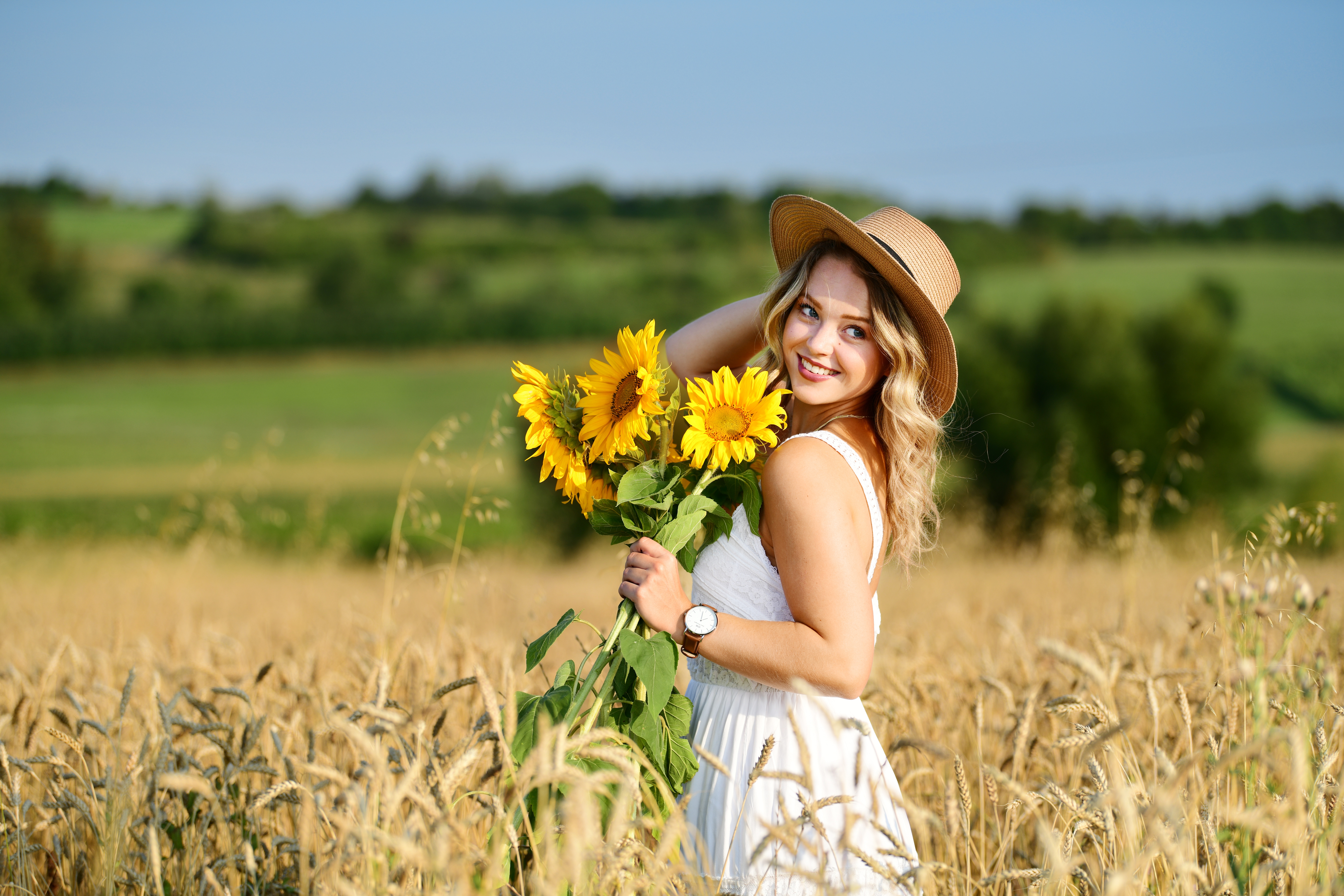 Wallpaper Smiling girl on the field with wheat with a bouquet of sunflowers in hand.