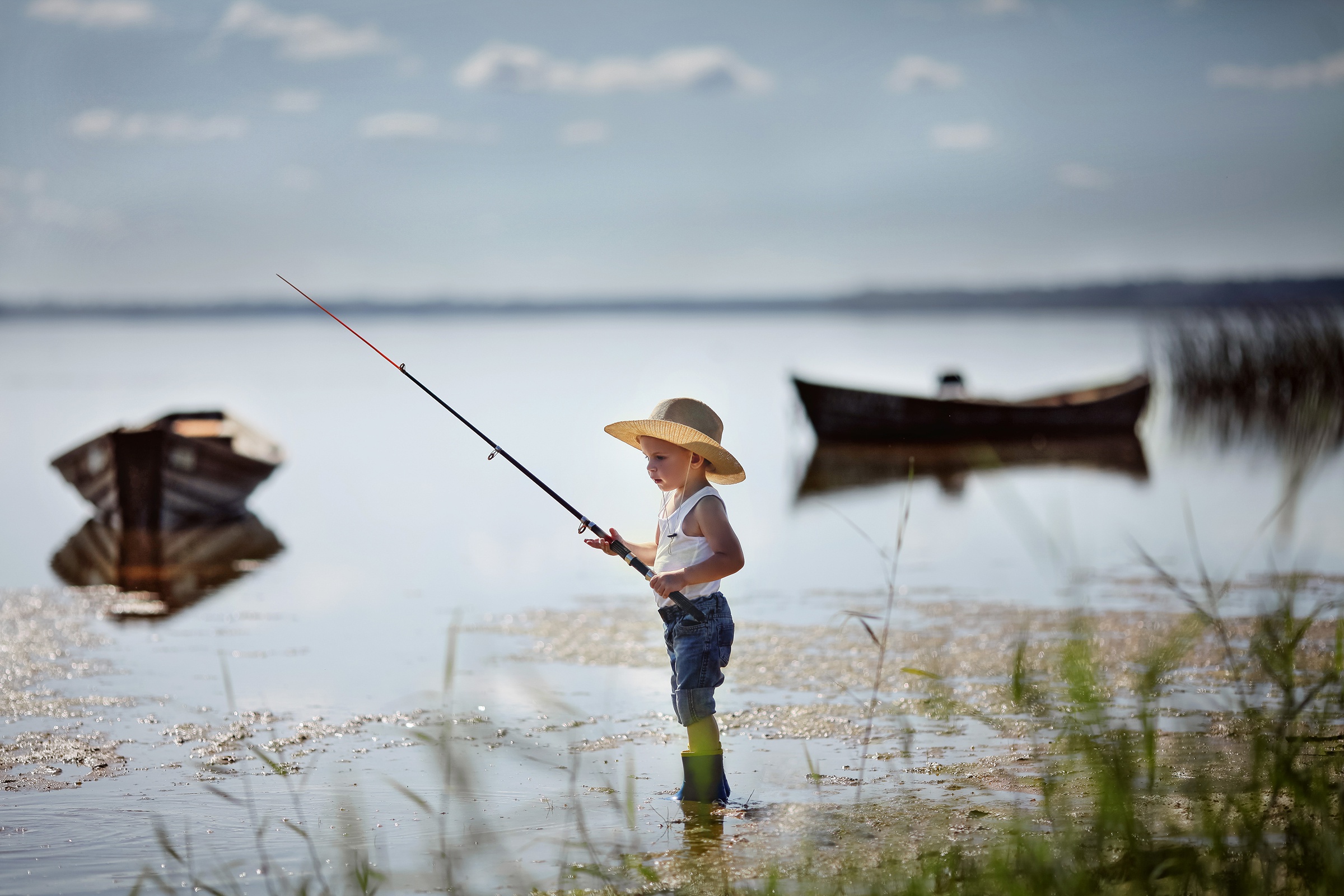 Wallpaper Little boy in a hat fishes in the lake.